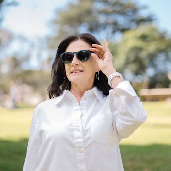 Woman in white polo and watch smiles outdoors while wearing Dresden Vision Canada polarised sunglasses – combining sun safety with effortless Canadian style.