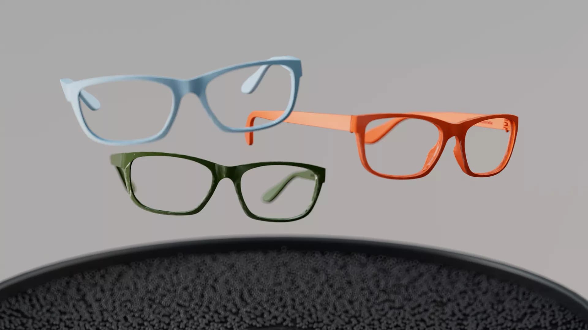 Three pairs of Dresden Vision eyewear in light blue, orange, and dark green, set in a staggered display on a dark textured surface. The modern, rectangular frames against a light gray background highlight stylish, sustainable eyewear available in Canada.