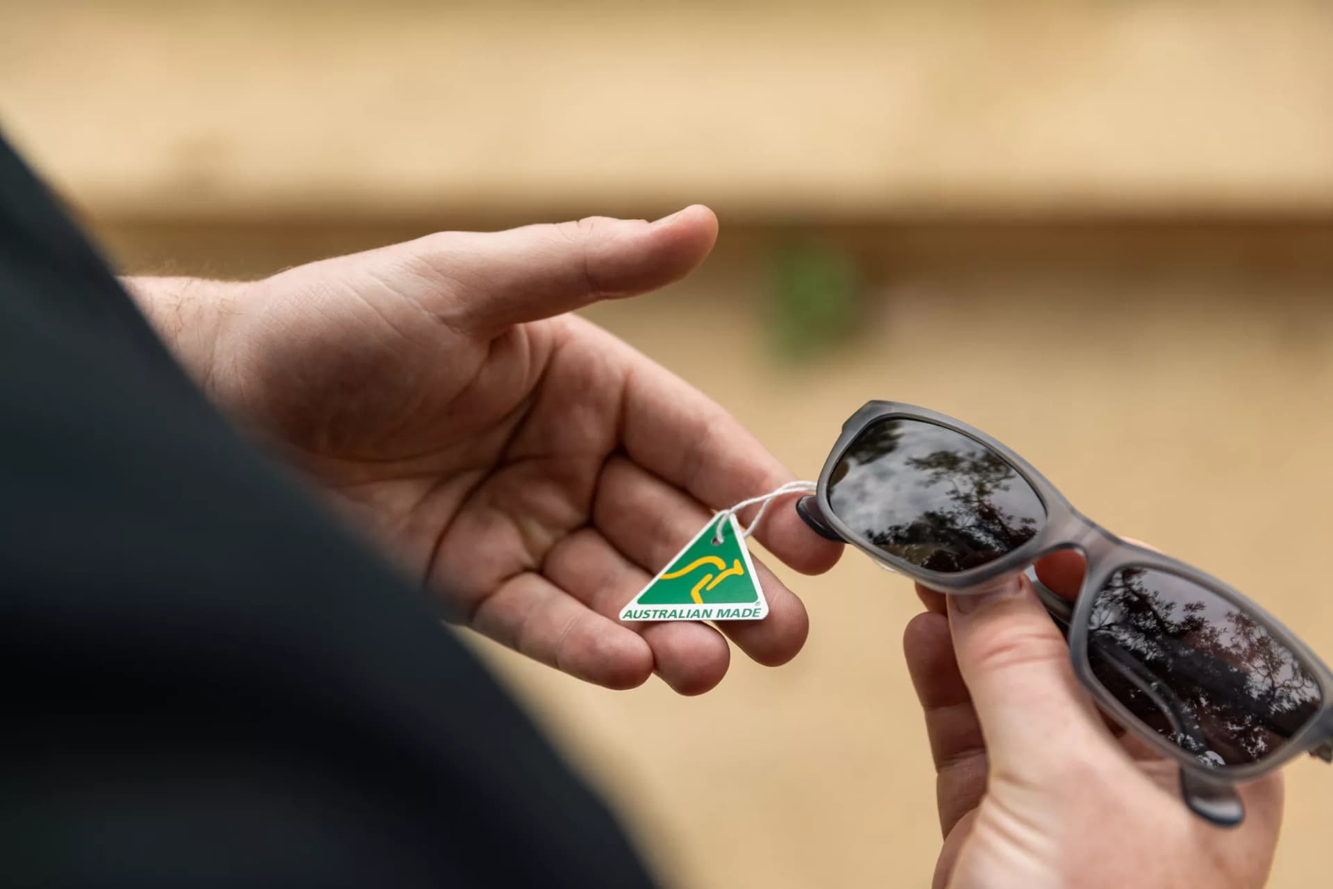 Close-up of hands holding Dresden Vision Prescription Glasses with an Australian Made tag, highlighting the quality and craftsmanship of our eyewear. The image emphasizes using insurance to purchase Dresden Vision glasses online in Canada.