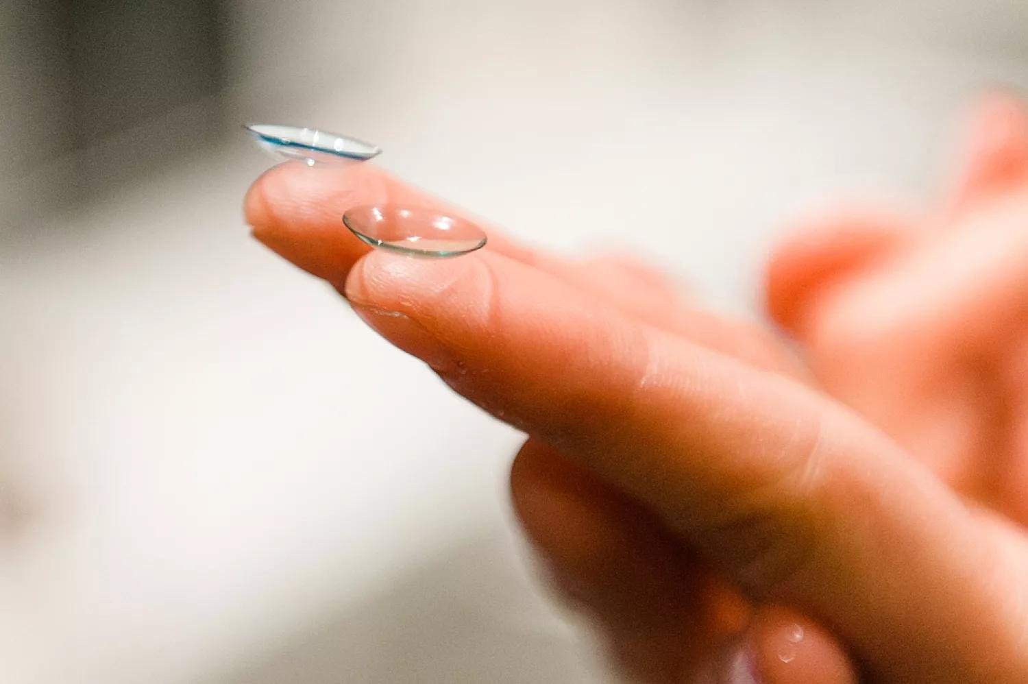 A close-up of a hand holding a contact lens on the tip of the index finger. It highlights the delicate nature of handling contact lenses in Australia.