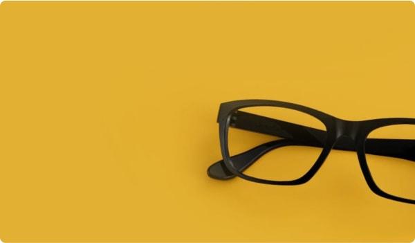 Dresden Vision's classic black frames set against a bold yellow backdrop, reflecting the stylish yet practical eyewear favored in New Zealand.